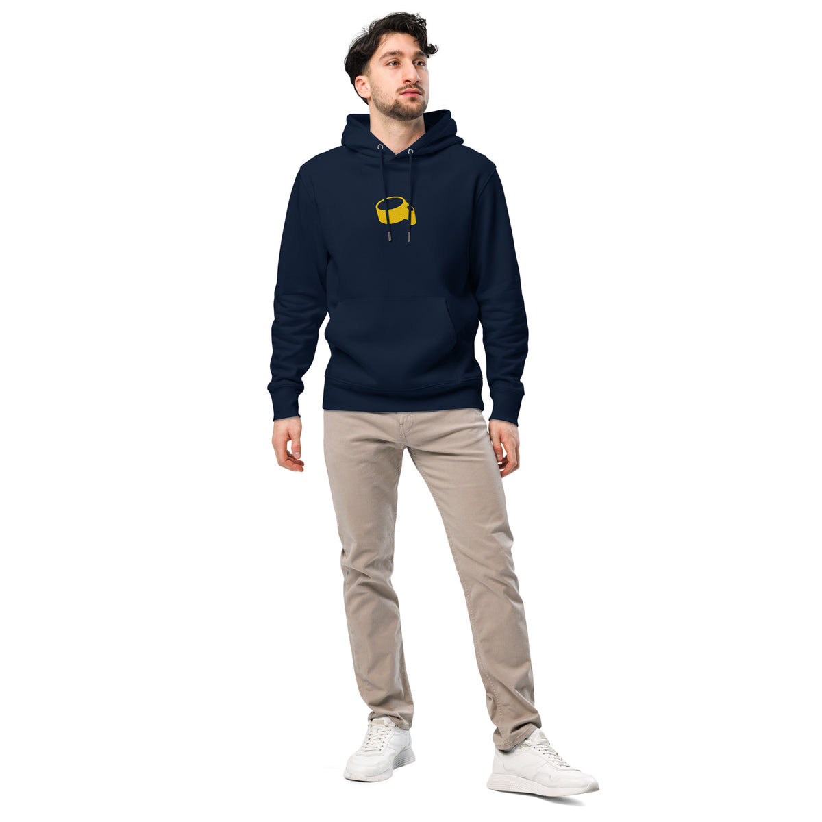 Model in de donkerblauwe hoodie met de gele korf, met lichte broek en witte schoenen